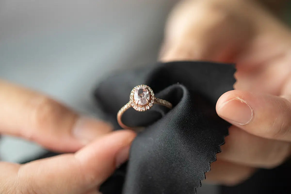 Diamond ring held on a black cloth by a person's hand